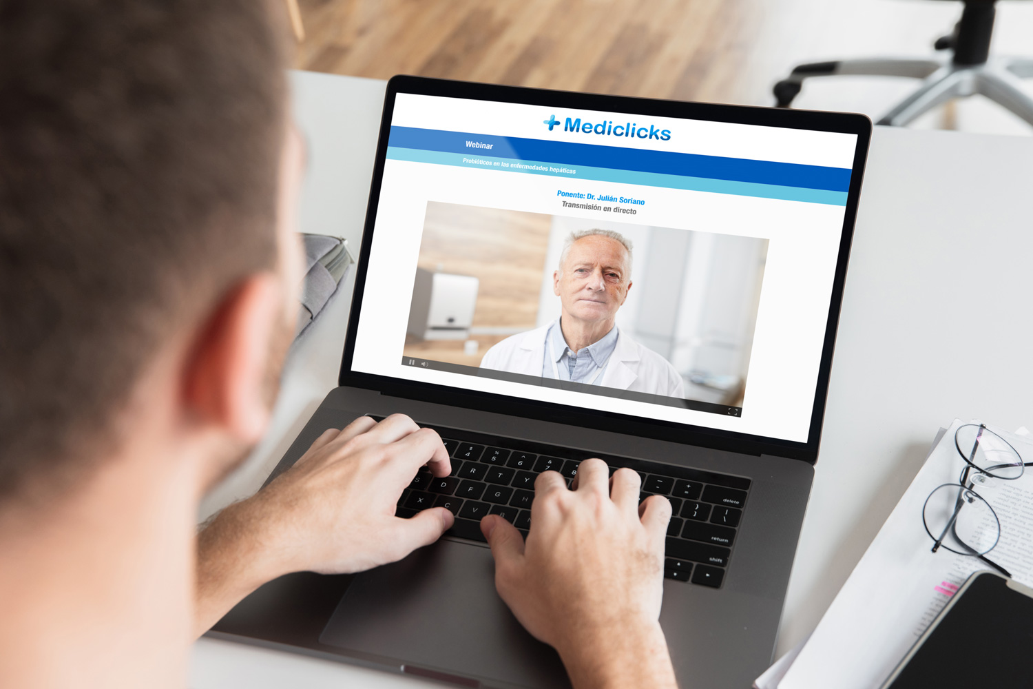 Hombre escuchando un webinar online de + Mediclicks con su portátil